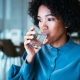 Woman sipping on water in clear glass in the middle of the night