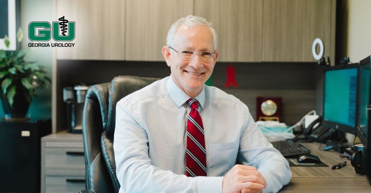 Dr. Andrew Kirsch sitting at desk with arms crossed on desktop, smiling