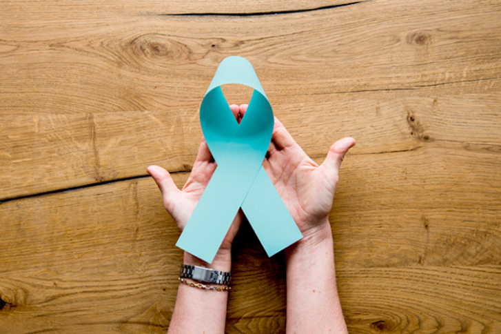 Two hands holding an oversized prostate cancer ribbon.
