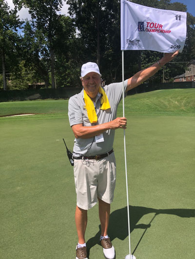 Volunteer, Bob Weyand, holding a TOUR Championship flag at the East Lake golf course.
