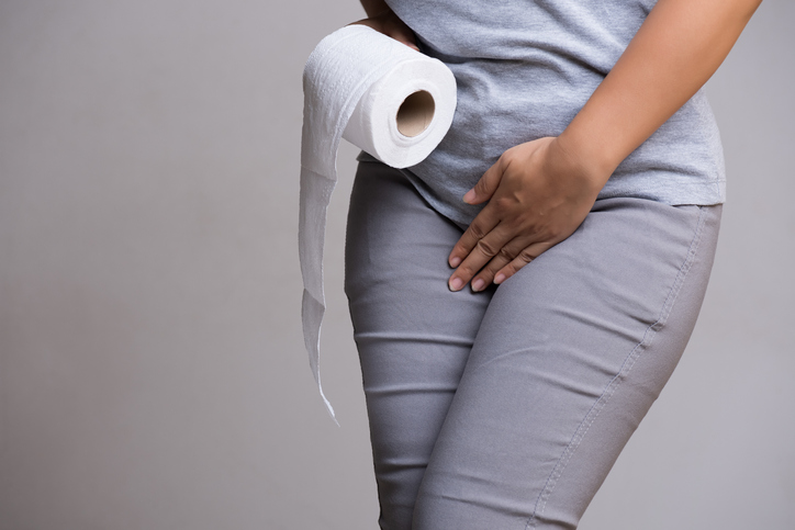 Woman hand holding her crotch lower abdomen and tissue or toilet paper roll. Disorder, Diarrhea, incontinence. Healthcare concept, dealing with overactive bladder.