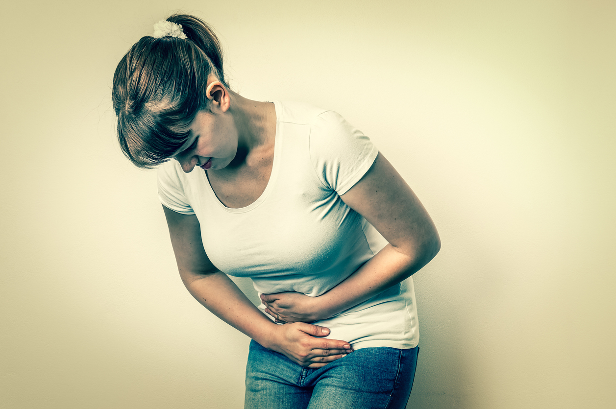 Woman with menstrual pain is holding her aching belly - isolated on white background, wondering why do bladders fall.