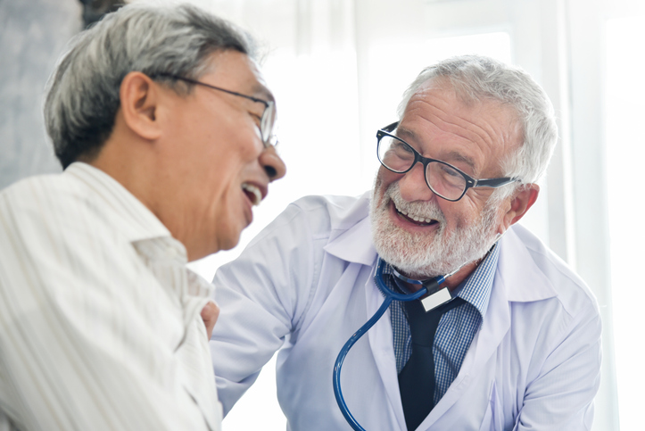 Happiness People. Senior male Doctor and Asian male patient are talking in the medical room together. Smiling, discussing prostate cancer rehabilitation treatments.
