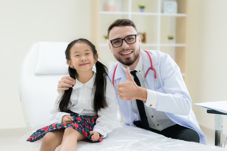 Doctor with cute little girl showing thump up OK signs in hospital. Medicine and health care concept., discussing Can A Child Get a UTI or a VUR.