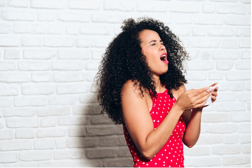 african american woman sneezing, stress urinary incontinence